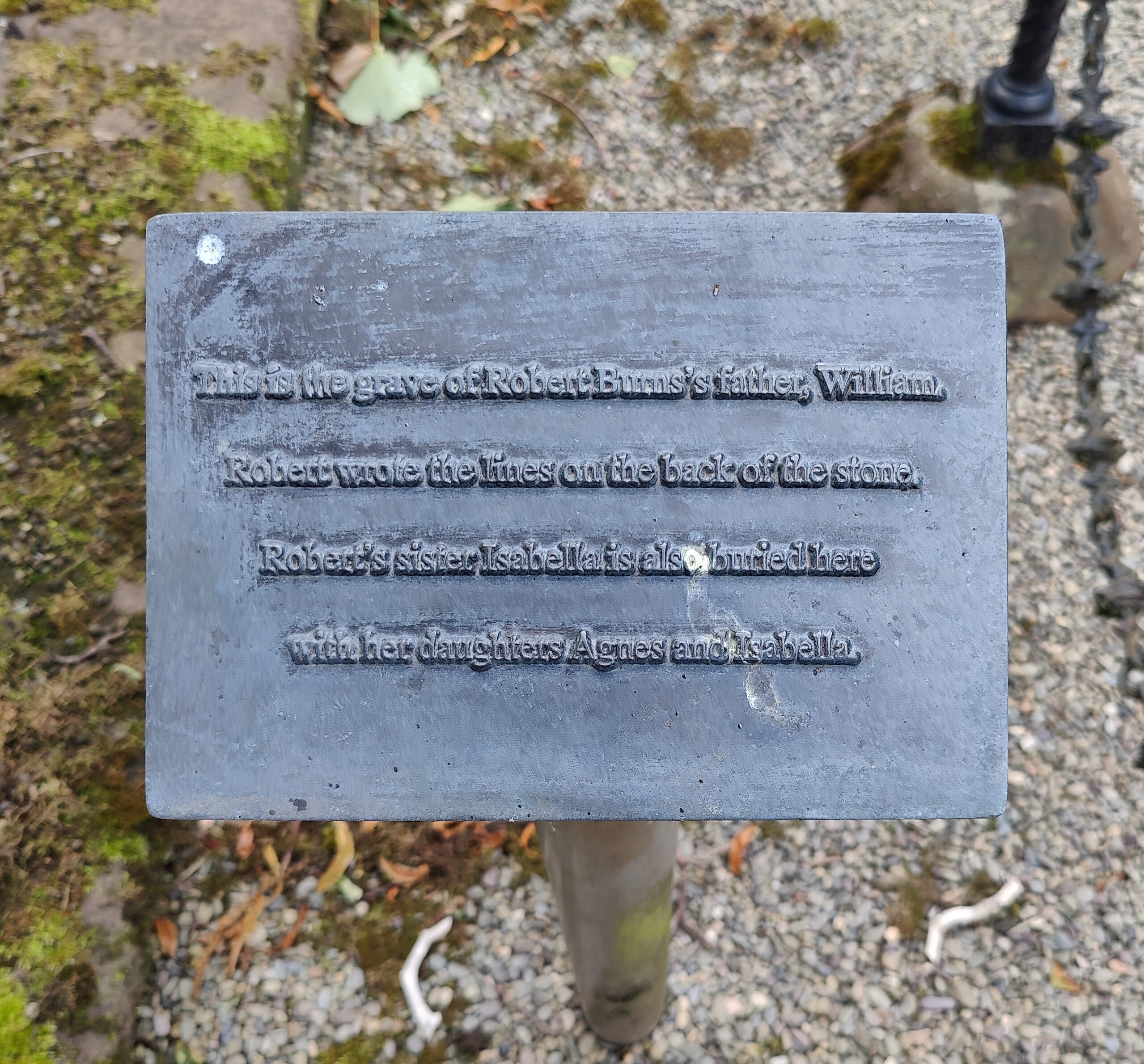 A plaque reads "This is the grave of Robert Burns's father, William. Robert wrote the lines on the back of the stone. Robert's sister Isabbella is also buried here with her daughters Agnes and Isabella.